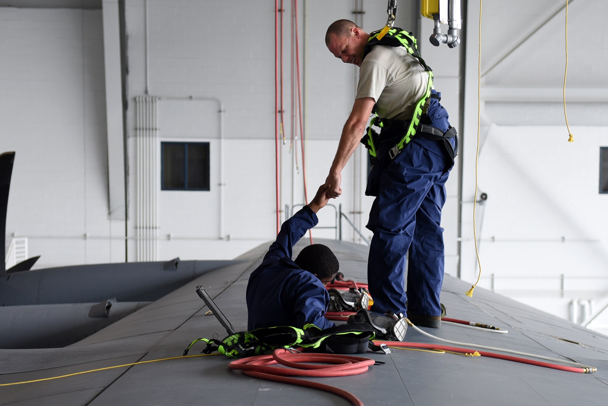 Tech Sgt. Darel Somer, 19th Maintenance Squadron fuel systems craftsman, assists Senior Airman Stefan Stephenson-Shipp, 19th Maintenance Squadron fuels system journeyman, exit a C-130J dry bay Aug. 8, 2017, at Little Rock Air Force Base, Ark. Airmen performing or assisting with maintenance on a dry bay must be harnessed for protection in case they fall. (U.S. Air Force photo by Airman 1st Class Kevin Sommer Giron)