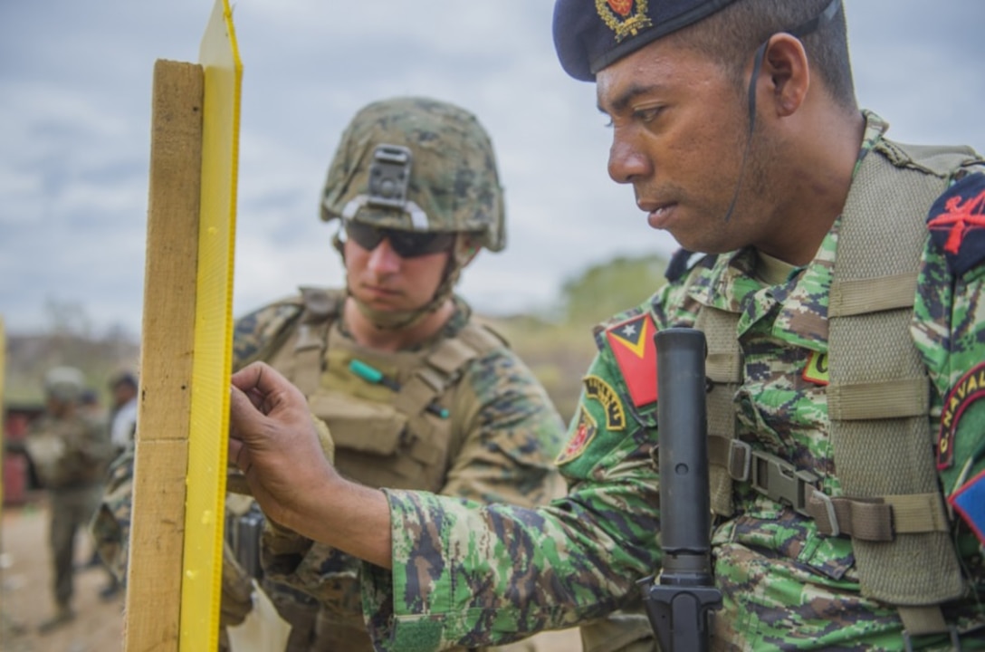 METINARO TRAINING BASE, Timor-Leste (July 31, 2017) - Cpl. Trevor Hoffman,
Fleet Anti-Terrorism Security Team Pacific, Marine Corps Security Forces Regiment, helps Timor-Leste
Navy Soldado Agustinho Guterres cover bullet holes in a range target at Metinaro Training Base, Timor-Leste, during Cooperation Afloat Readiness and Training (CARAT) Timor-Leste 2017. CARAT is a bilateral exercise series which provides a credible venue for the U.S. Navy and it’s eight partner nations to share best practices and rehearse cooperation in response to shared maritime security challenges. (Official photograph by U.S. Navy Petty Officer 1st Class Martin Wright/released)