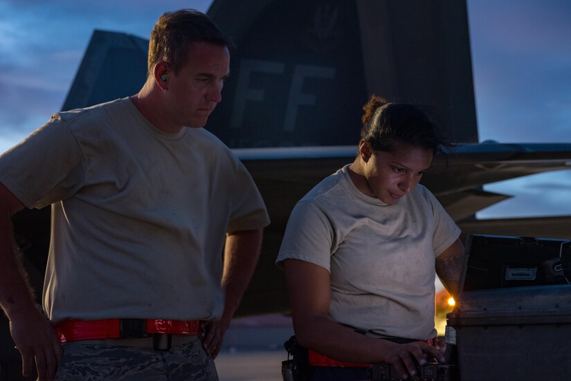 U.S. Air Force Staff Sgt. Christopher Wilson and Senior Airman Maza Nurya, 27th Aircraft Maintenance Unit crew chiefs, review technical orders for the F-22 Raptor, while preparing to launch aircraft during Red Flag 17-4, at Nellis Air Force Base, Nev. Aug. 14, 2017. (U.S. Air Force Photo/Staff Sgt. Carlin Leslie)