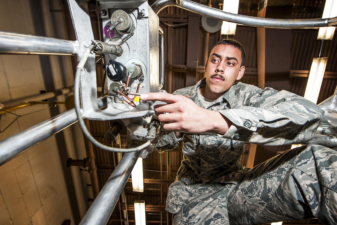 An airman inspects a metal device on a guided missile maintenance platform.