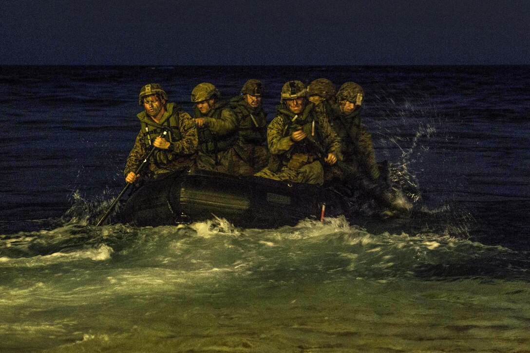 Marines paddle in a rubber raiding craft at night during an exercise in the Coral Sea.