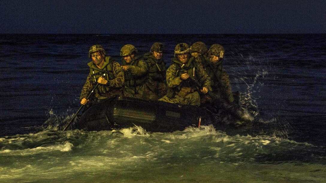 Marines paddle in a rubber raiding craft at night during an exercise in the Coral Sea.