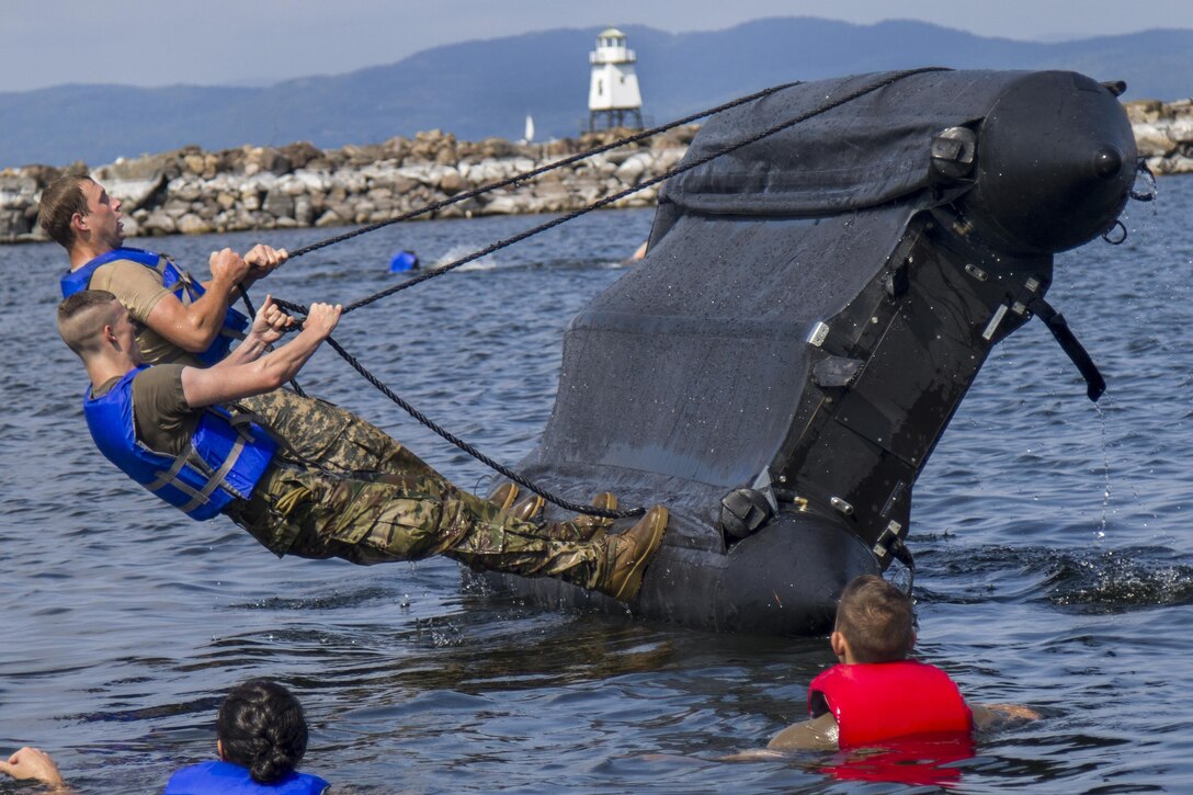 Soldiers lean back on a zodiac boat during capsizing training in the water.