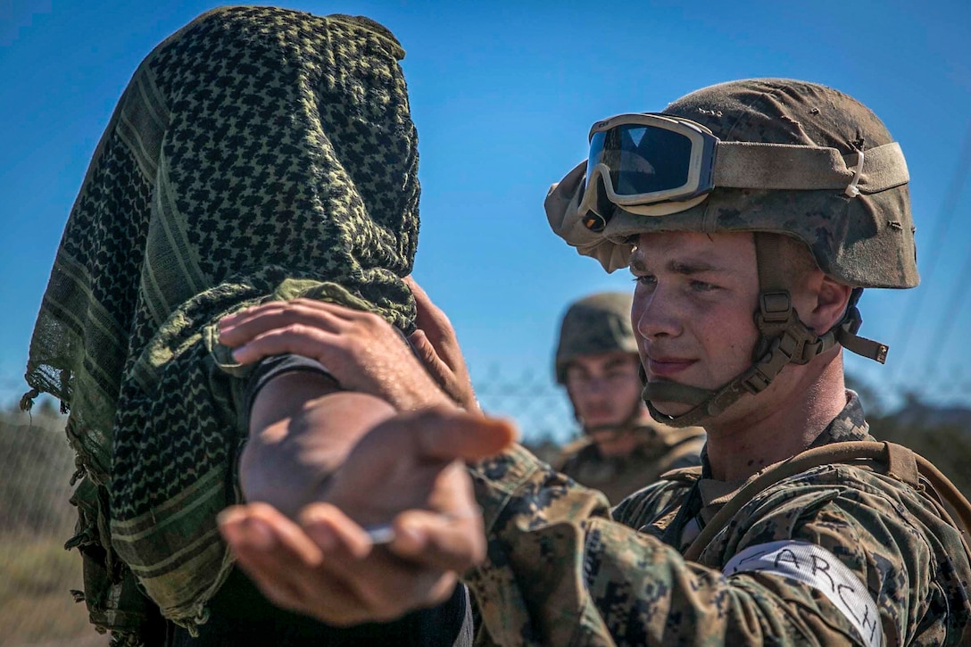 This image shows a Marine searching a person playing a role during an exercise.