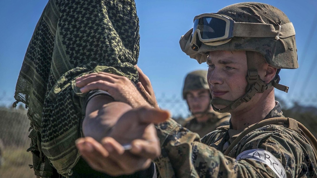 This image shows a Marine searching a person playing a role during an exercise.