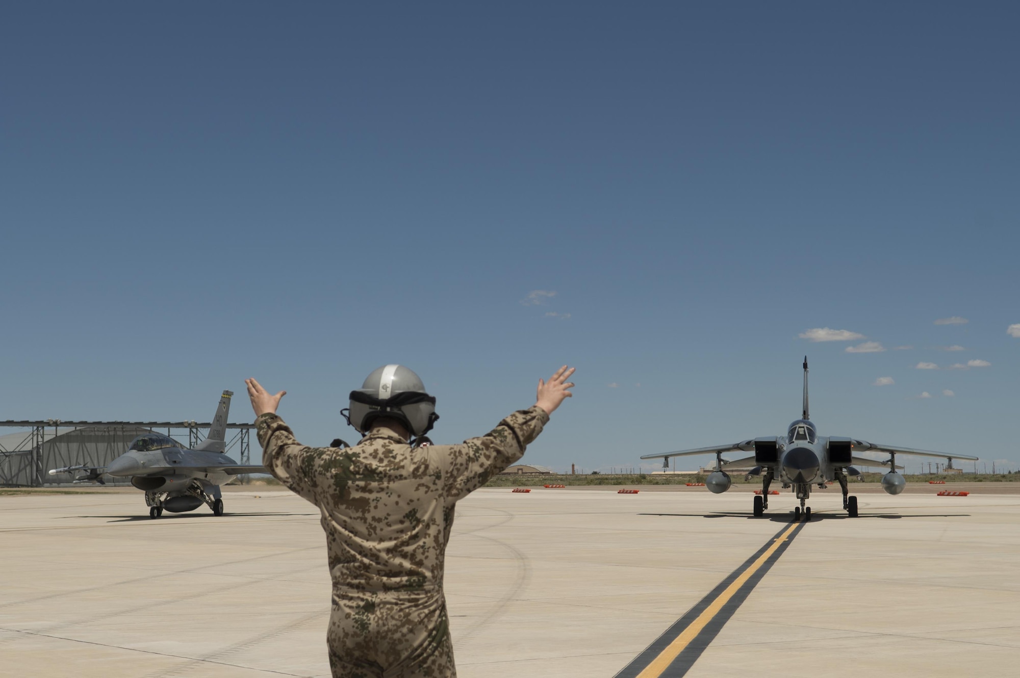 A German air force crew chief guides a GAF Tornado in with an F-16 Fighting Falcon assigned to the 314th Fighter Squadron during the last joint flying mission together here at Holloman Air Force Base, N.M., Aug. 17, 2017. The GAF has entered its final stage of departure, however they will not complete their departure until mid 2019. (U.S. Air Force photo by Tech. Sgt. Amanda Junk)