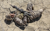 A recruit from Charlie Company, 1st Recruit Training Battalion, crawls under barbed wire during the Bayonet Assault Course at Marine Corps Recruit Depot San Diego, Aug. 8.