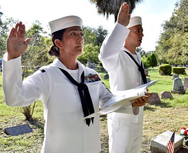 Petty Officer 1st Class Kimberly Garza (left) and Petty Officer 1st Class Michael Garcia, both Hospital Corps instructors and CPO selects, lead current and former hospital corpsmen in the Hospital Corps Pledge during an Aug. 15 graveside memorial service in San Antonio honoring Seaman John E. “Jackie” Kilmer, who was posthumously awarded the Medal of Honor June 18, 1953.