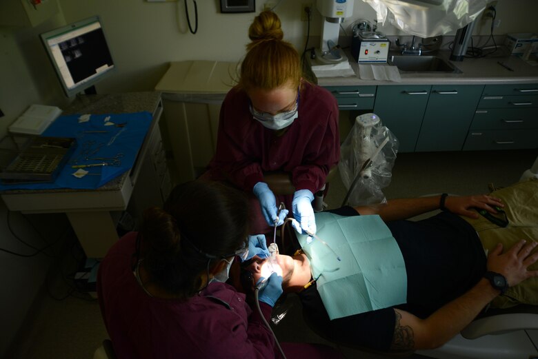 Air Force Maj. Nicole Smith (left), 673d Dental Squadron prosthodontist, and Senior Airman Lauren Francis, 673d DS dental technician (top), prepare Airman 1st Class Ian McKinney’s, 673d Security Forces Squadron alarm monitor specialist, teeth for a temporary crown at the Joint Base Elmendorf-Richardson Hospital, Alaska, Aug. 14, 2017. A cavity or incomplete tooth needs a crown to prevent further damage. The dentist removes any decay and the outer layer of the tooth so the crown fits like a cap.