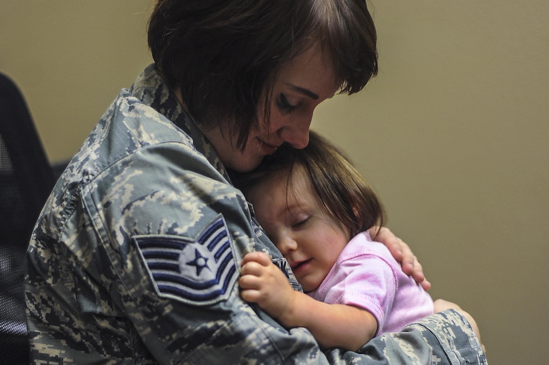 A softly smiling mother holds her softly smiling baby girl.