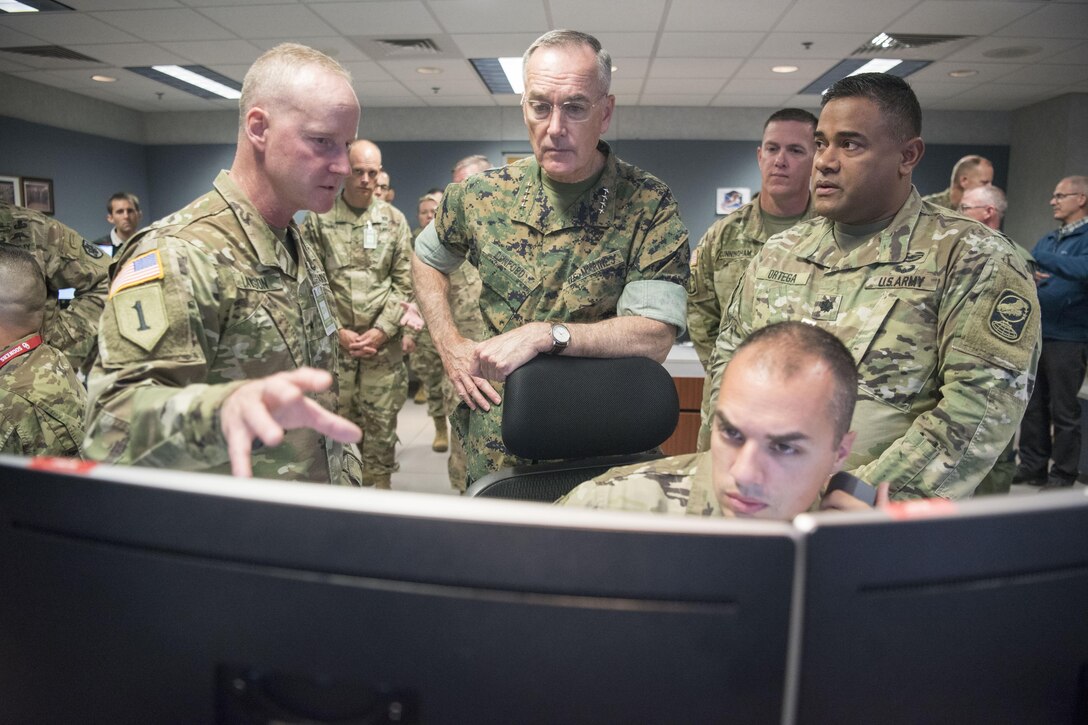 Soldiers stand around a computer monitor.