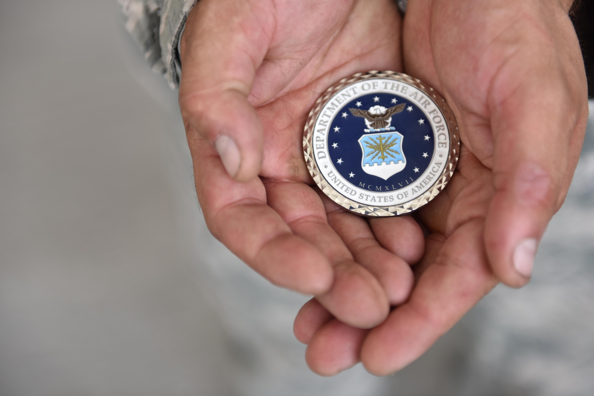 Staff Sgt. Kyle Yoder of the 380th Expeditionary Aircraft Maintenance Squadron holds out a coin awarded to him by Secretary of the Air Force Heather Wilson at Al Dhafra Air Base, United Arab Emirates, Aug. 18, 2017.