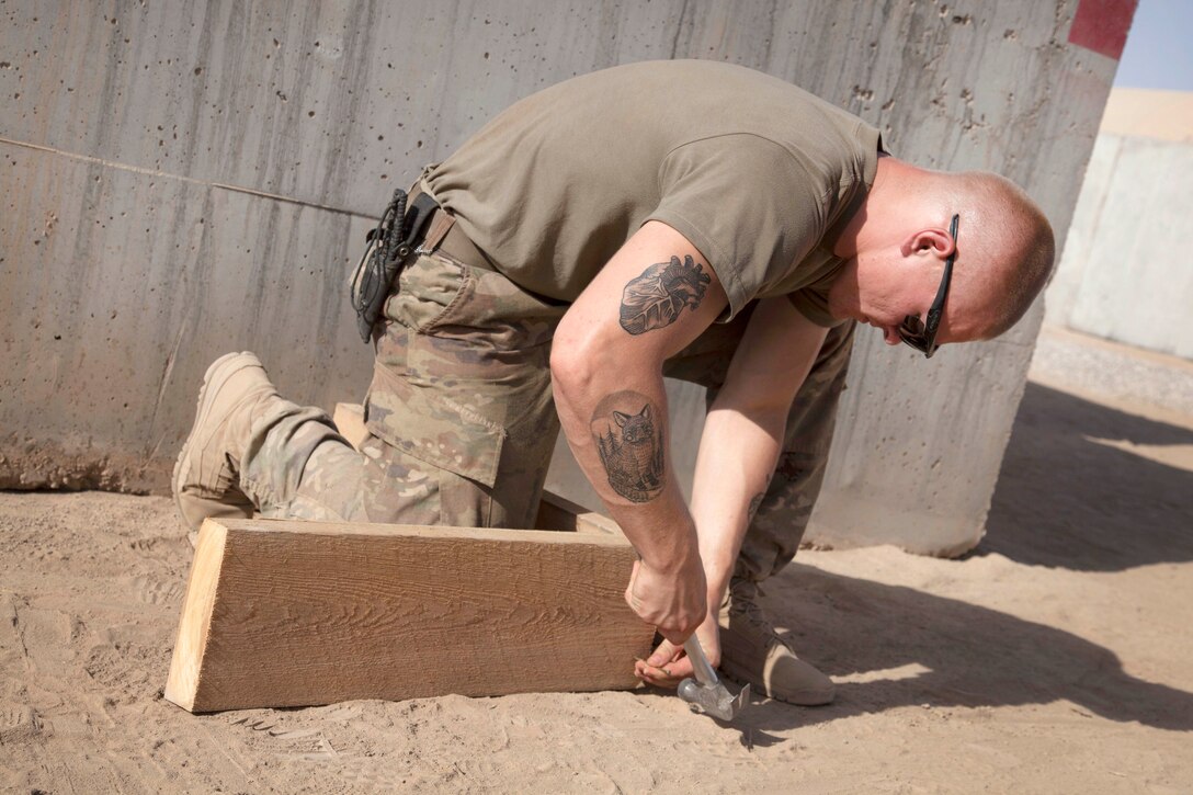 A soldier hammering boards.
