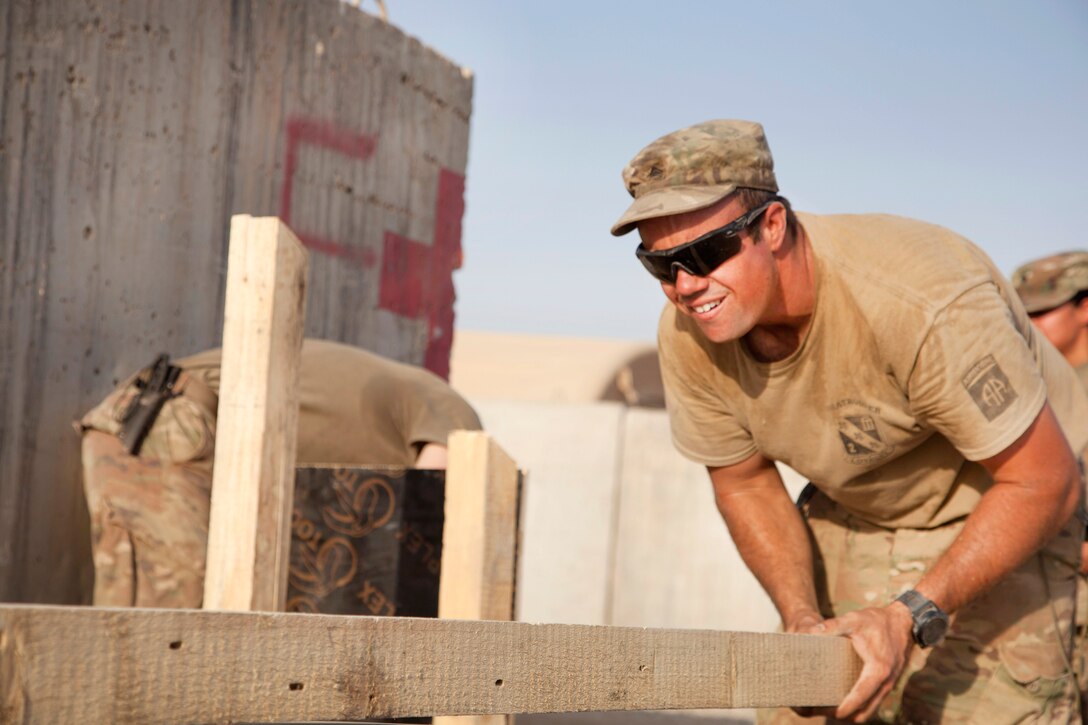 A soldier aligns a board while building a podium.