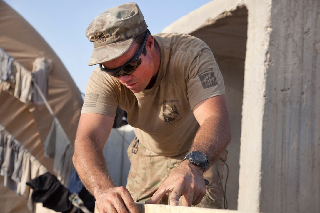 A soldier connects boards while building a podium.