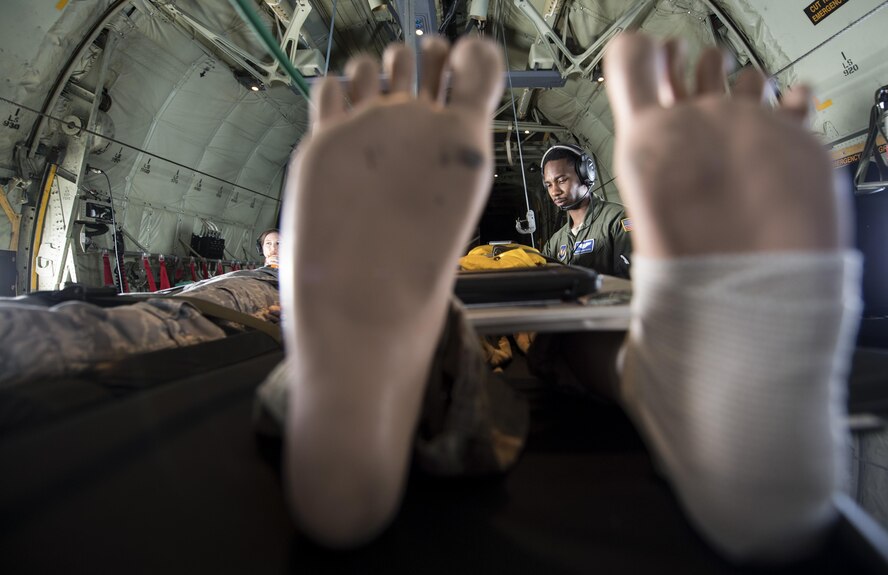 U.S. Air Force Staff Sgt. Tedario Cassel, 86th Aeromedical Evacuation Squadron aeromedical evacuation technician, examines a medial dummy during a training mission while flying to Ramstein Air Base, Germany, Aug. 17, 2017. Four medical dummies were used during the aeromedical training mission for the 86th AES Airmen to practice procedures to maintain readiness. (U.S. Air Force photo by Senior Airman Tryphena Mayhugh)