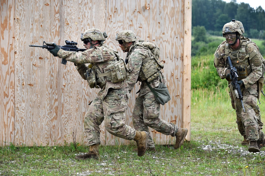 Soldiers approach buildings during a combined arms live-fire exercise.