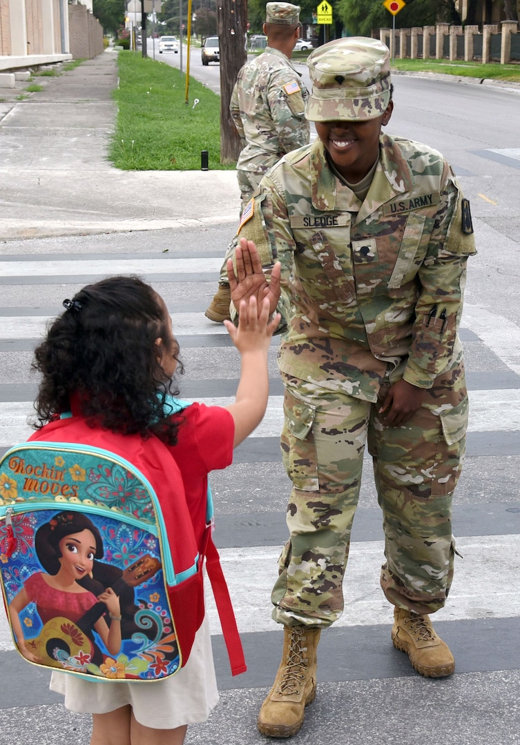 Spc. Toni Sledge from the 470th Military Intelligence Brigade at Joint Base San Antonio-Fort Sam Houston high fives one of the students on their walk in to school. She was posted as road guard during the first day of school at Bowden Elementary School.