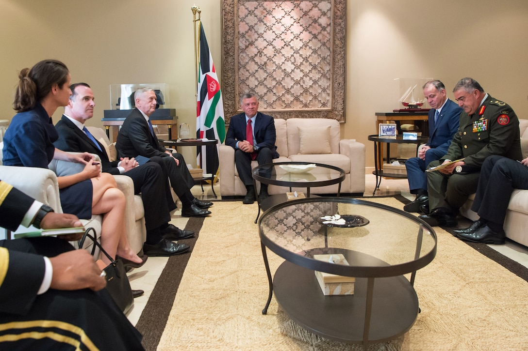 Defense Secretary Jim Mattis and the king of Jordan speak while a group of people sit in the room. 