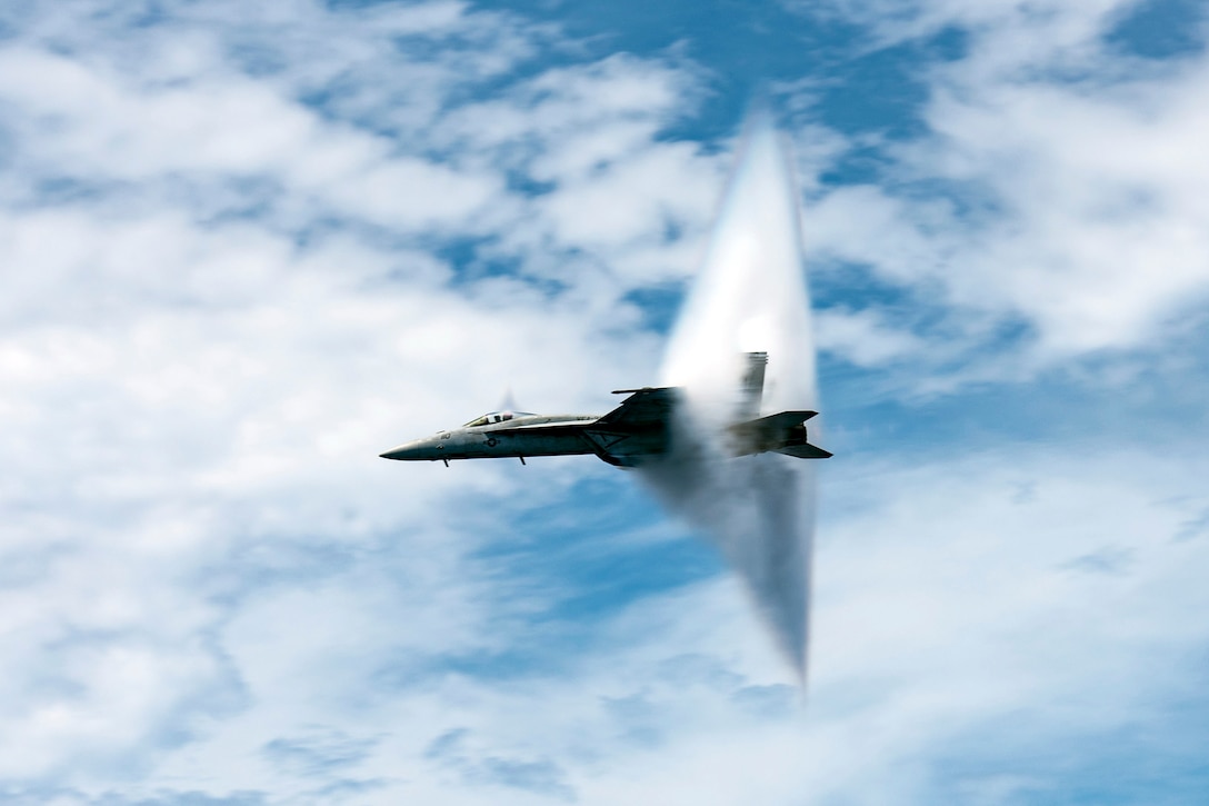 An aircraft bursts through a triangular cloud as the plane breaks the sound barrier.