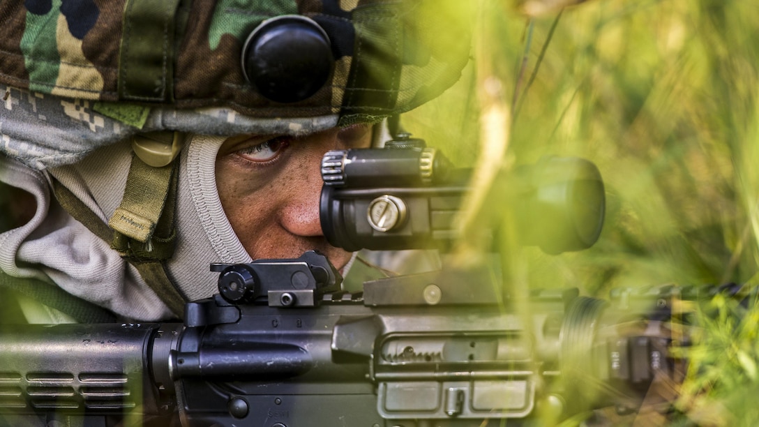 An airman looks down the scope of a rifle during an outdoor exercise.