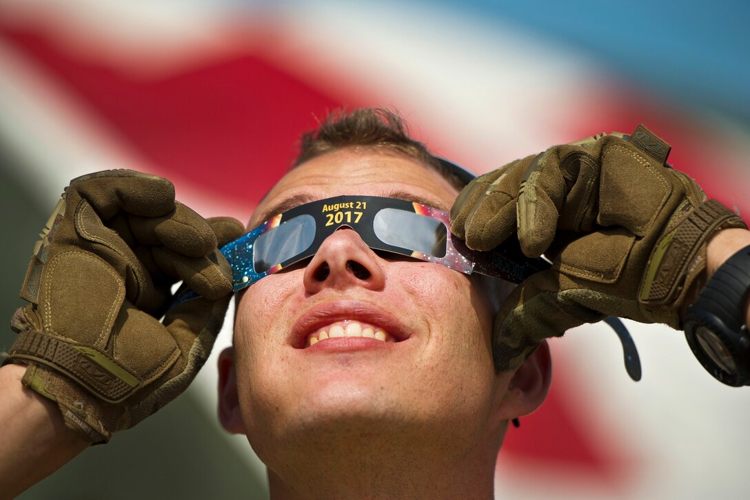 An airman watches the solar eclipse through eclipse glasses.
