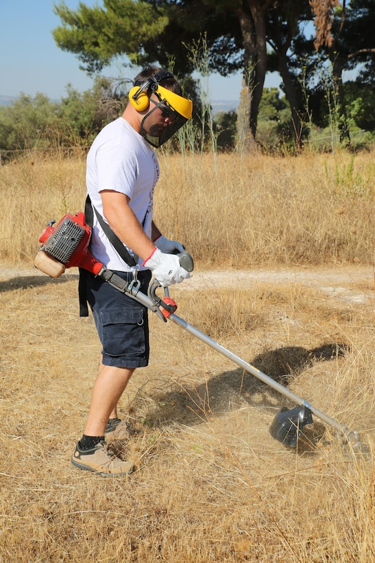 A Marine with Special Purpose Marine Air-Ground Task Force-Crisis Response-Africa logistics combat element cuts grass using a weed-whacker during a clean-up event at the Eurialo Castle in Siracusa, Italy, Aug 3, 2017. Marines and Sailors with SPMAGTF-CR-AF LCE joined Italian volunteers in restoring the 2,400 year-old ancient piece of history. (U.S. Marine Corps photo by Lance Cpl. Patrick Osino)