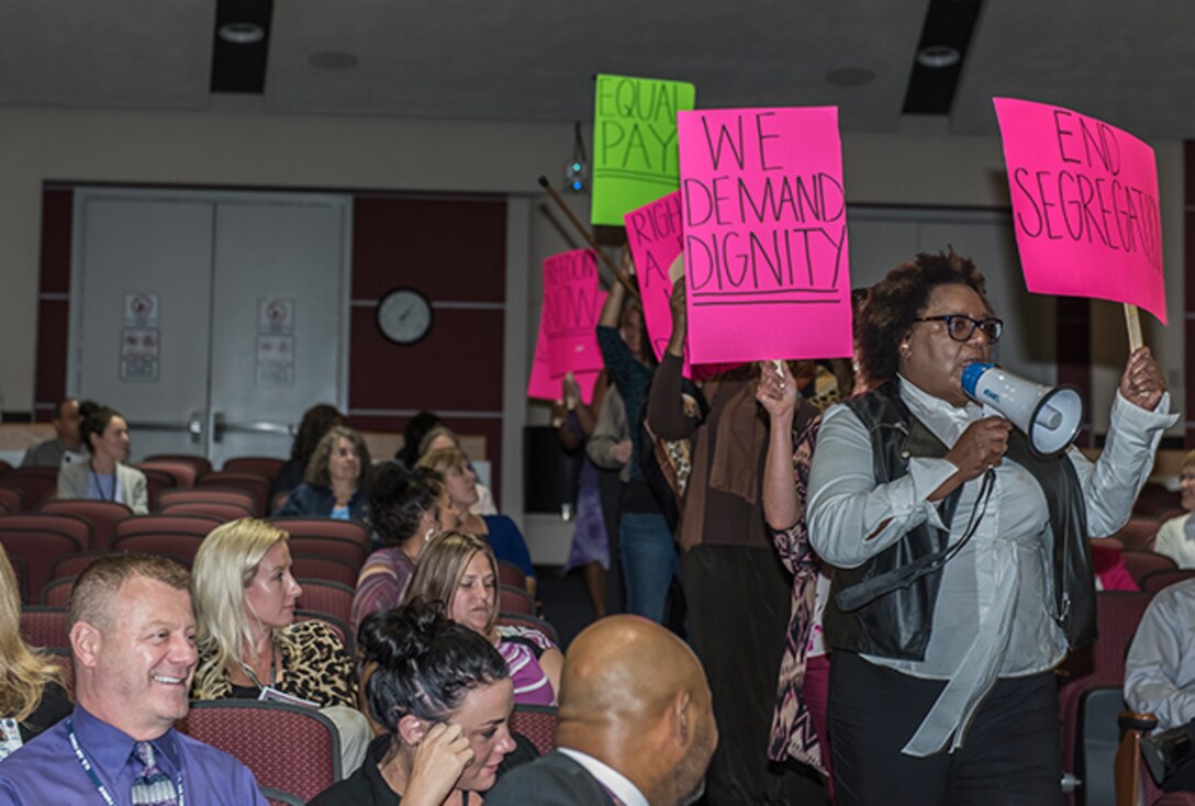 Members of the cast depict a protest march supporting an equal rights for women initiative.