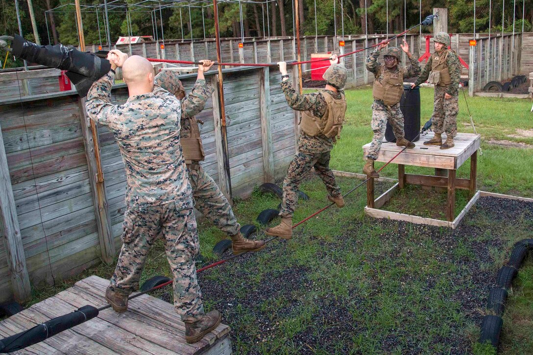 Marines climb across a rope bridge obstacle.