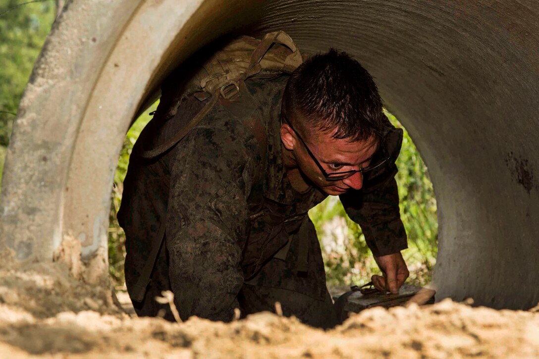 Marine Corps Cpl. Christopher A. Baxter crawls through a culvert