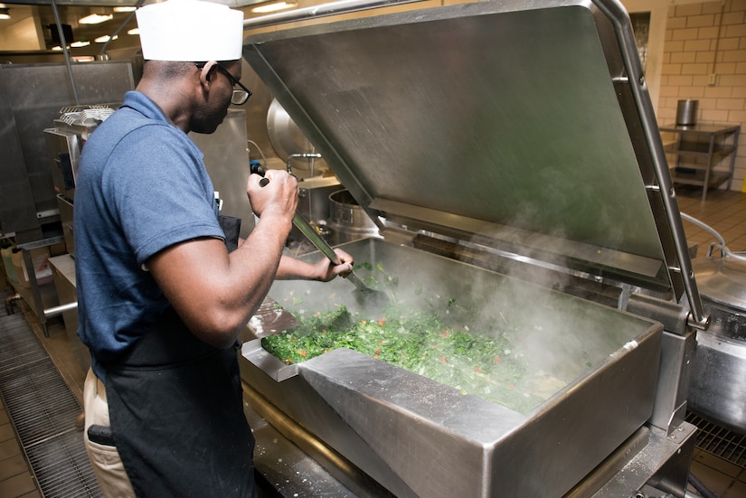 Soldier cooks large quantity of spinach.