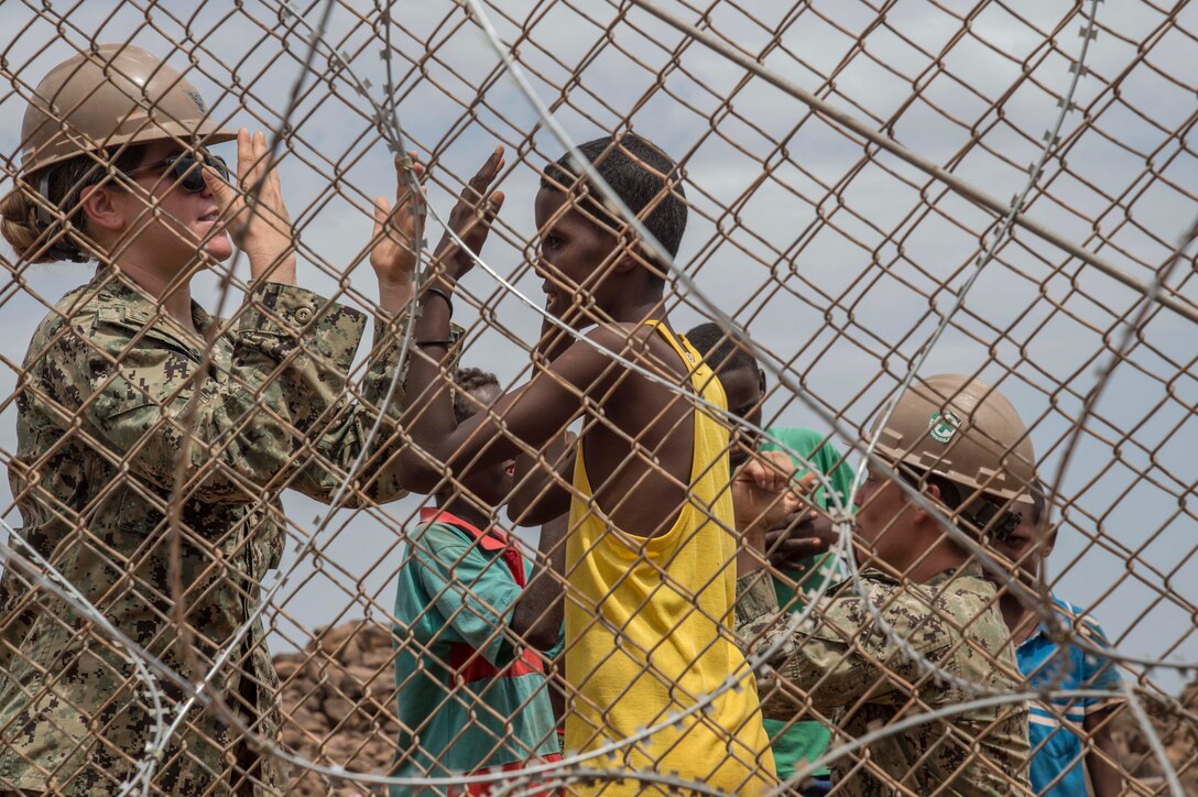 Navy Seabees Petty Officer 3rd Class Lacy P'Pool and Petty Officer 3rd Class Cayla George, assigned to Combined Joint Task Force Horn of Africa, play with local children on a construction site in Djibouti's Arta region, Aug. 17, 2017. The project was started by Naval Mobile Construction Battalion 1, and NMCB 133 will continue working on the project, with plans of completion in 2018. Air National Guard photo by Air Force Tech. Sgt. Joseph Harwood