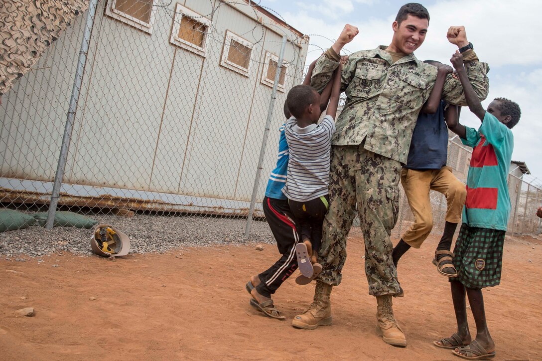 Navy Seabees Seaman Jesse Martinez, assigned to Combined Joint Task Force Horn of Africa, plays with local children on a construction site in Djibouti's Arta region, Aug. 17, 2017. The project was started by Naval Mobile Construction Battalion 1, and NMCB 133 will continue working on the project, with plans of completion in 2018. Air National Guard photo by Air Force Tech. Sgt. Joseph Harwood