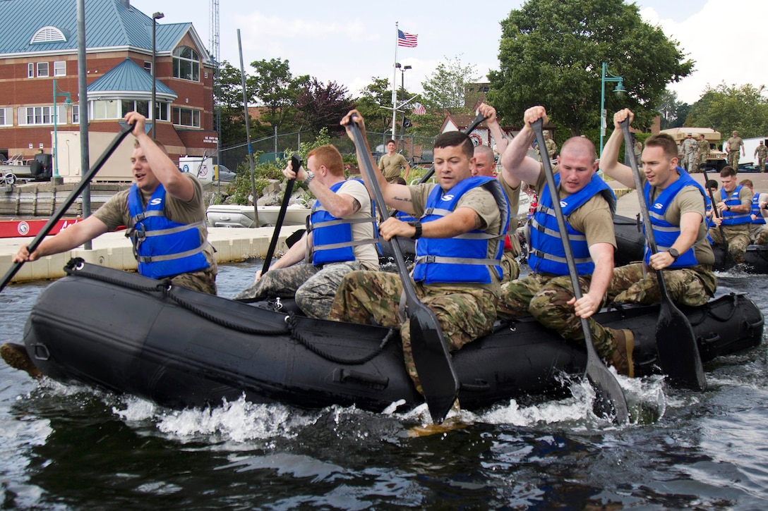 Guardsmen paddle through the water in zodiac boats.