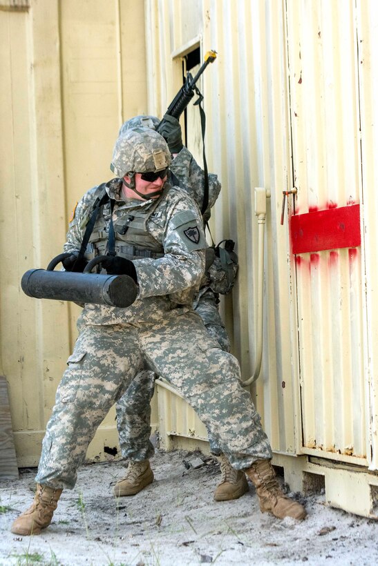 A soldier conducts a forced entry of a building.