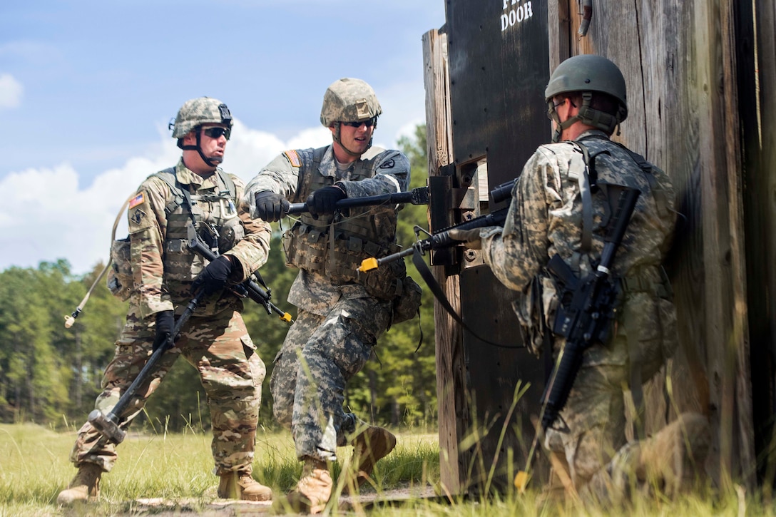 Soldiers conduct a forced entry using a halligan tool.