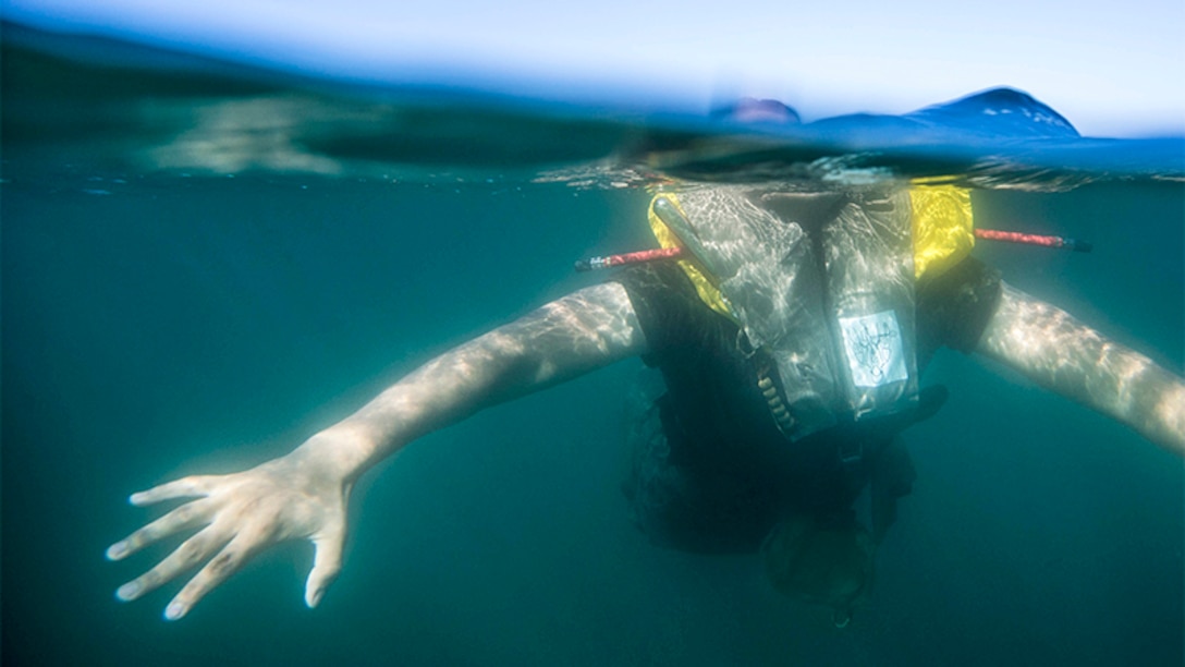 This image shows a Marine swimming with a life vest during a surf qualification.