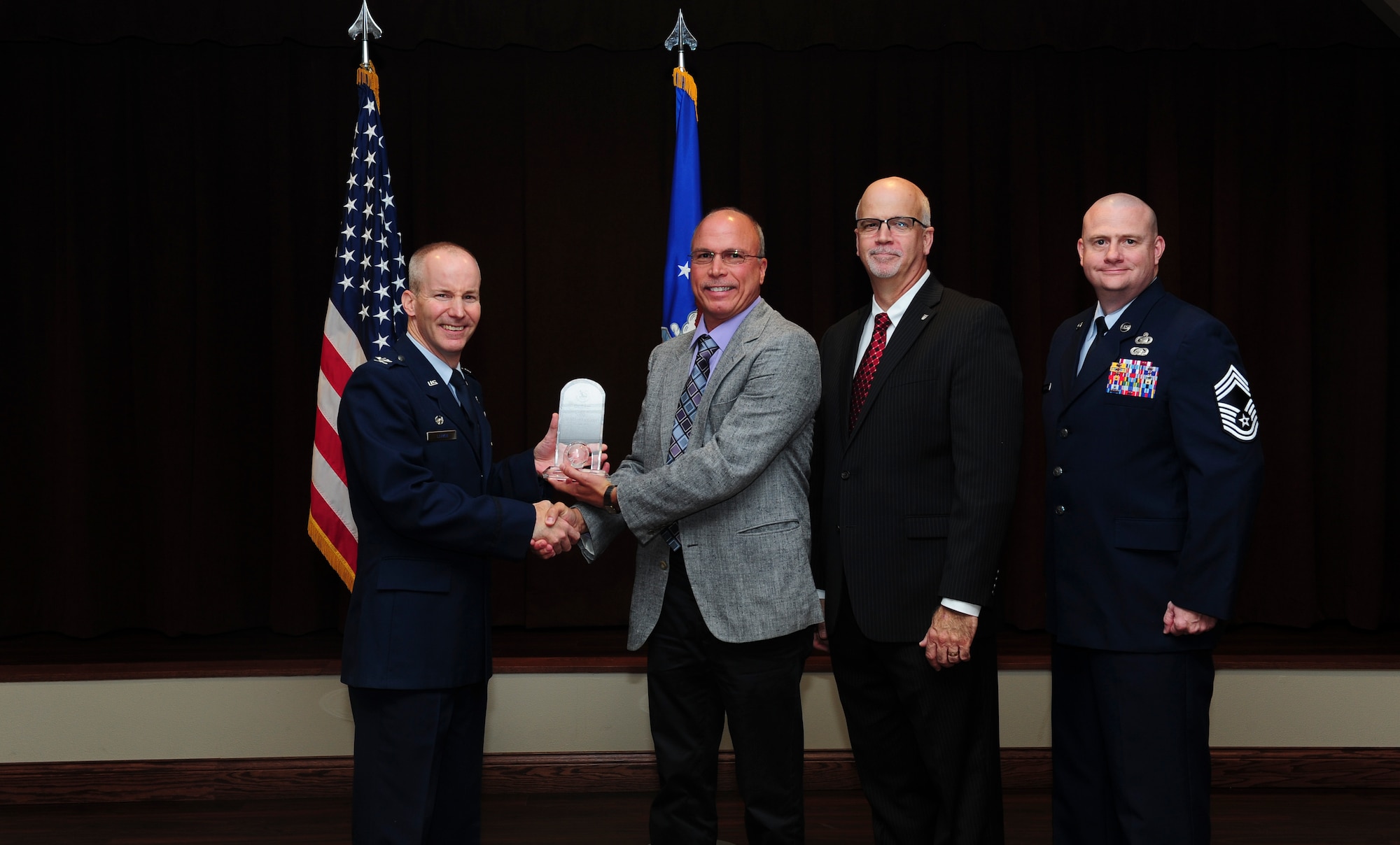 Steve Marcum, National Air and Space Intelligence Center employee, receives the NASIC Wall of Honor award from Col. Sean Larkin, NASIC commander and Curt Rowland, NASIC chief scientist, here Aug. 15, 2015. The Wall of Honor is the greatest honor that NASIC can bestow on one of its alumni, It recognizes their significant achievements and is a reflection of their lasting, positive contributions to the center. (U.S. Air Force photo by Staff Sgt. Stephanie Longoria)