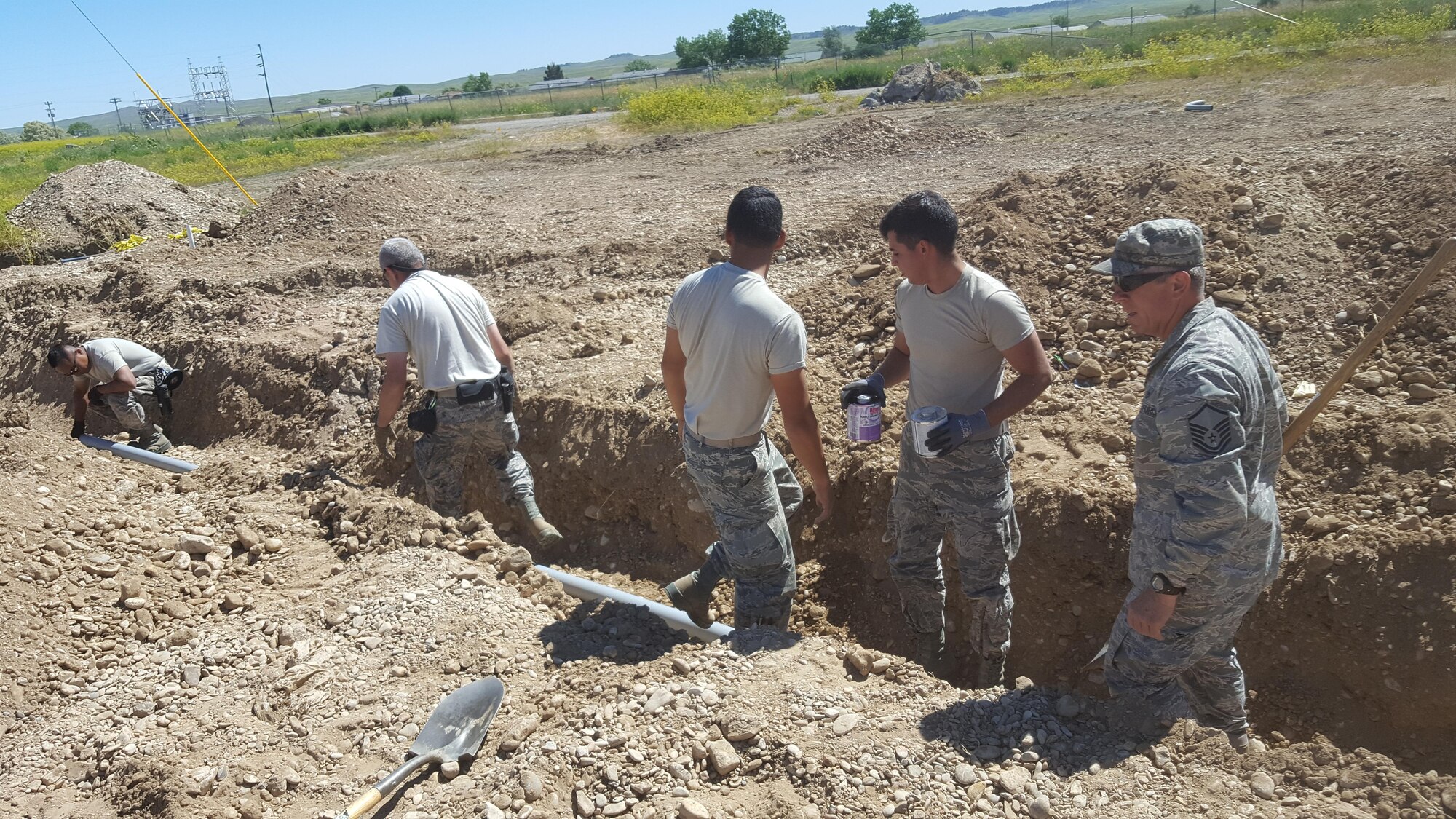 Members of the 106th Rescue Wing Civil Engineering assigned to the New York Air National Guard, dig a ditch for a pipeline at Crow Agency, Montana June 13, 2017. The effort to build and renovate homes for military service veterans of the Native American tribe Crow Nation started in May and will end in September of this year. (U.S. Air Force photo by Airman 1st Class Jonathan De Jesus)