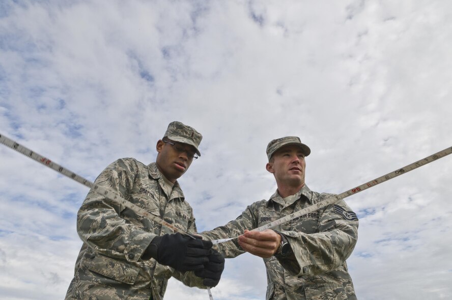 U.S. Air Force 2nd Lt. Justin Drayton, left, 307th Civil Engineer Squadron, Barksdale AFB, La., and Staff Sgt. Brandon Grove, assigned to the 302nd Civil Engineer Squadron, Peterson AFB, Colo., measure out a tent site for a bare base setup at Young Air Assault Strip, Fort McCoy, Wis., Aug. 4, 2017, during exercise Patriot Warrior.