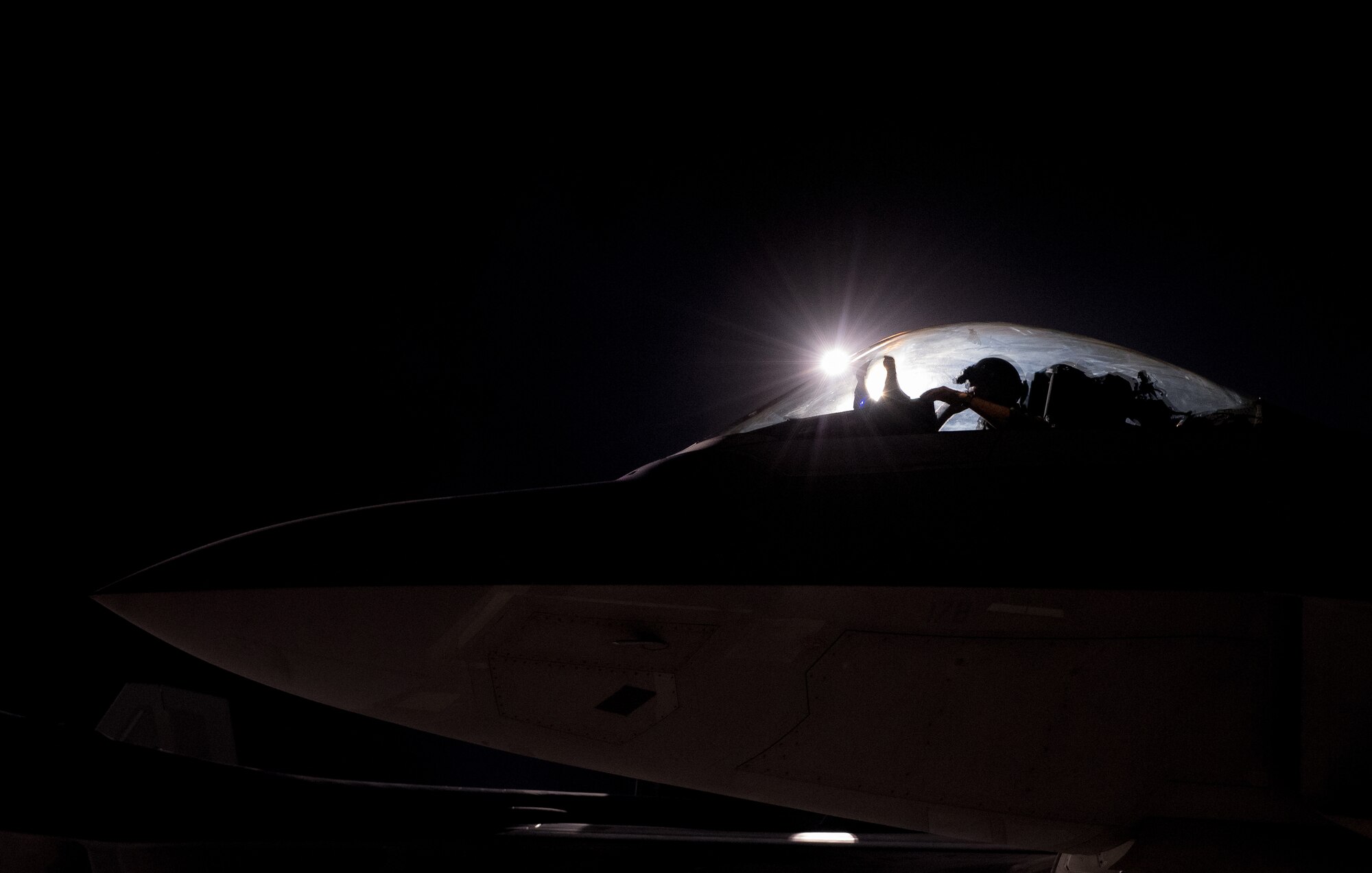 An U.S. Air Force F-22 Raptor from the 94th Fighter Squadron blocks the airfield light while taxing out for mission at Nellis Air Force Base, Nev., August 21m 2017. The 94th FS is taking part in Red Flag 17-4, a multi-platform air and ground combat scenario. (U.S. Air Force photo by Staff Sgt. Carlin Leslie)