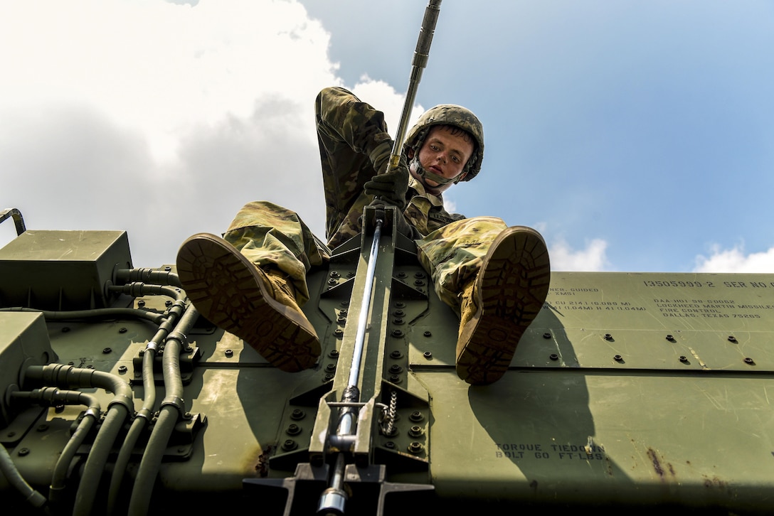 A soldier tightens a bolt on a weapon system.