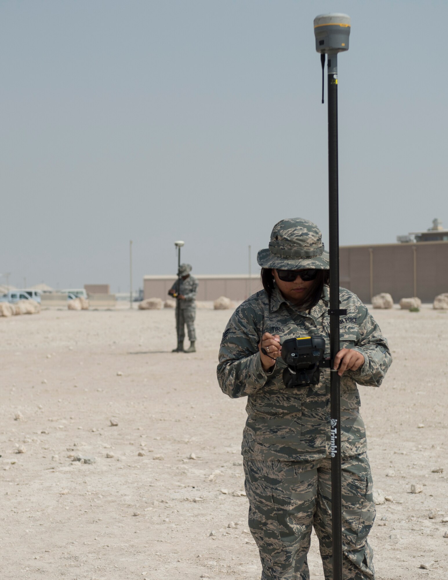 U.S Air Force Senior Airman Zamantha Tinio, front, an expeditionary geobase manager and Senior Airman Dalicia Brenson, an engineering technician with the 379th Expeditionary Civil Engineer Squadron, record the coordinates and elevations on the Trimble GPS Land Surveying Equipment at Al Udeid Air Base, Qatar, Aug. 2, 2017.
