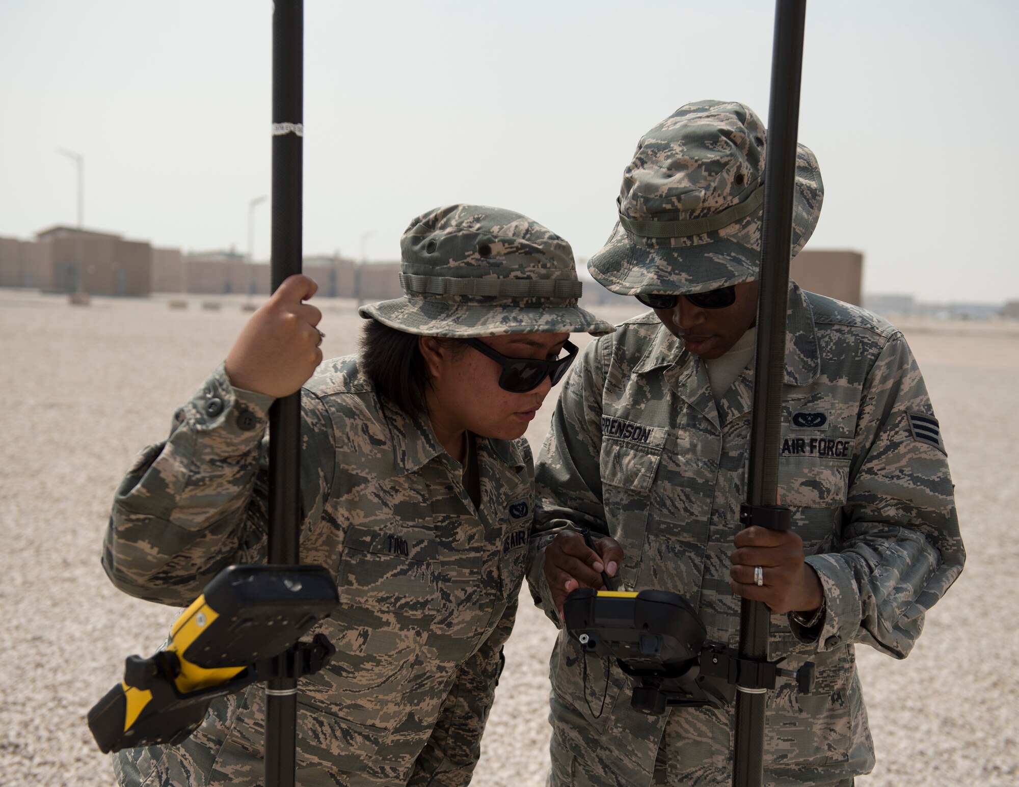 U.S Air Force Senior Airman Zamantha Tinio, left, an expeditionary geobase manager and Senior Airman Dalicia Brenson, an engineering technician with the 379th Expeditionary Civil Engineer Squadron, review the coordinates and elevations on the Trimble GPS Land Surveying Equipment at Al Udeid Air Base, Qatar, Aug. 2, 2017.