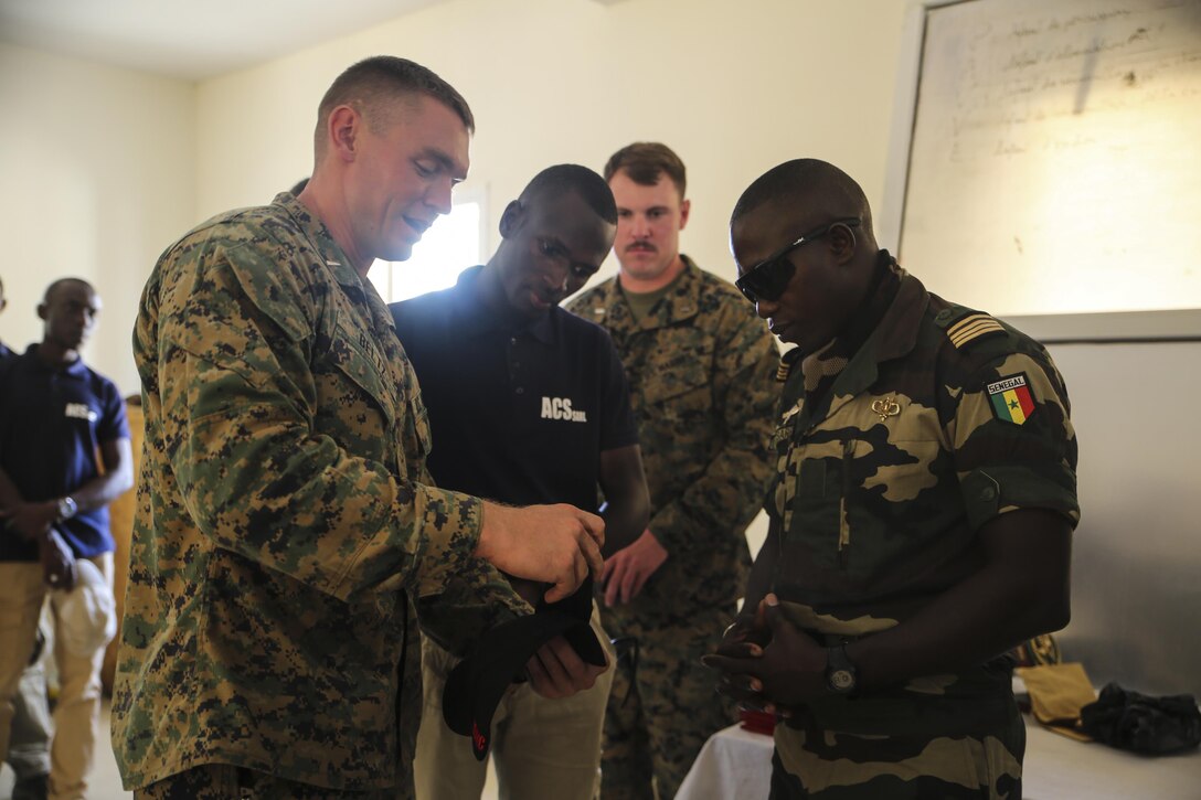 1st. Lt David Beltz, theater security cooperation Senegal team leader, presents a gift to Maj. Mamadou Sarr, base commander of Centre D’Entrainement Tactique Number 7, during the closing ceremony of a peacekeeping operations training mission at Thies, Senegal, June 16, 2017. Marines and Sailors with SPMAGTF-CR-AF served as instructors and designed the training to enhance the soldiers’ abilities to successfully deploy in support of United Nations peacekeeping missions in the continent. (U.S. Marine Corps photo by Sgt. Samuel Guerra/Released)