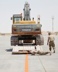 U.S. Air Force Staff Sgt. David Wakeman, laying down, airfield operator, and Master Sgt. Ricky Johnson, airfield superintendent, both assigned to the 557th Expeditionary RED HORSE Squadron, inspect a low-boy trailer and excavator before unloading the equipment on the runway at Al Udeid Air Base, Qatar, Aug. 7, 2017. The 557th ERHS loaded the 50,000 pound excavator into a C-17 Globemaster III aircraft for transportation to an undisclosed location in the U.S. Central Command Area of Responsibility. (U.S. Air National Guard photo by Tech. Sgt. Bradly A. Schneider/Released)