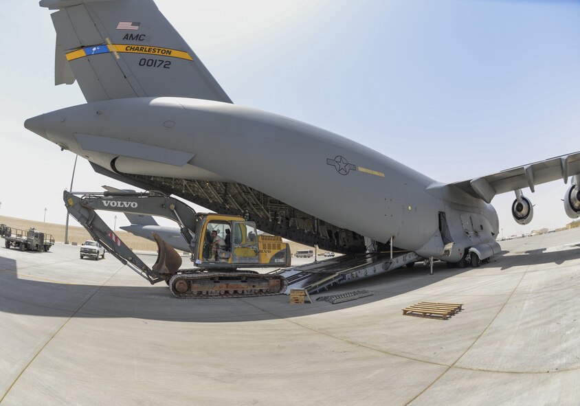 A excavator operated by U.S. Air Force Staff Sgt. David Wakeman, airfield operator assigned to the 557th Expeditionary RED HORSE Squadron, sits just outside a C-17 Globemaster III at Al Udeid Air Base, Qatar, Aug. 7, 2017.