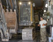 U.S. Air Force Technical Sgt. Alexander Nunez, standing, air transportation/cargo movement team non-commissioned officer in charge, and Staff Sgt. David Wakeman, seated inside the excavator, airfield operator, both assigned to the 557th Expeditionary RED HORSE Squadron, ease an excavator into a C-17 Globemaster III at Al Udeid Air Base, Qatar, Aug. 7, 2017. Members of the 557th ERHS loaded the 50,000 pound excavator into a C-17 Globemaster III aircraft for transportation to an undisclosed location in the U.S. Central Command Area of Responsibility. (U.S. Air National Guard photo by Tech. Sgt. Bradly A. Schneider/Released)