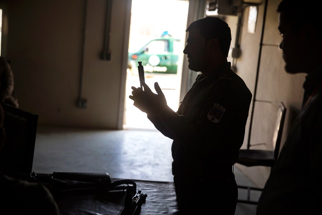 An Afghan National Police officer names each part of an M16A2 assault rifle