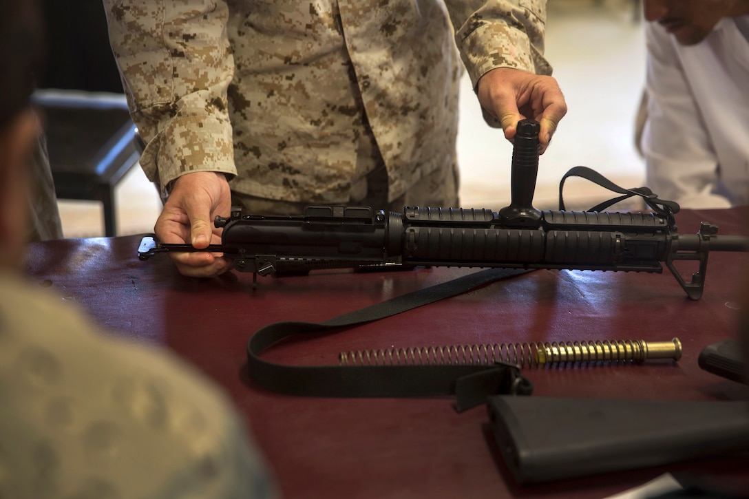 A U.S. Marine shows Afghan National police officers how to reassemble the M16A2 assault rifle.